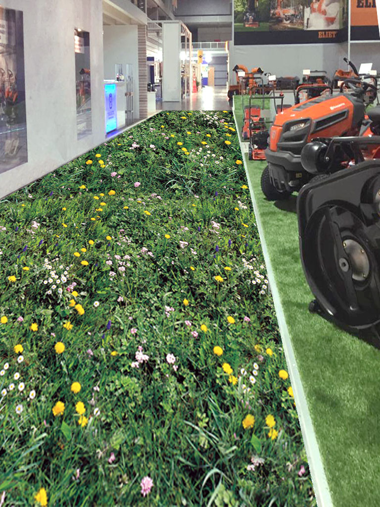 Realistischer Bodenbelag mit Blumenwiese als Laufweg neben Rasenmähern und Gartengeräten in einer Ausstellung