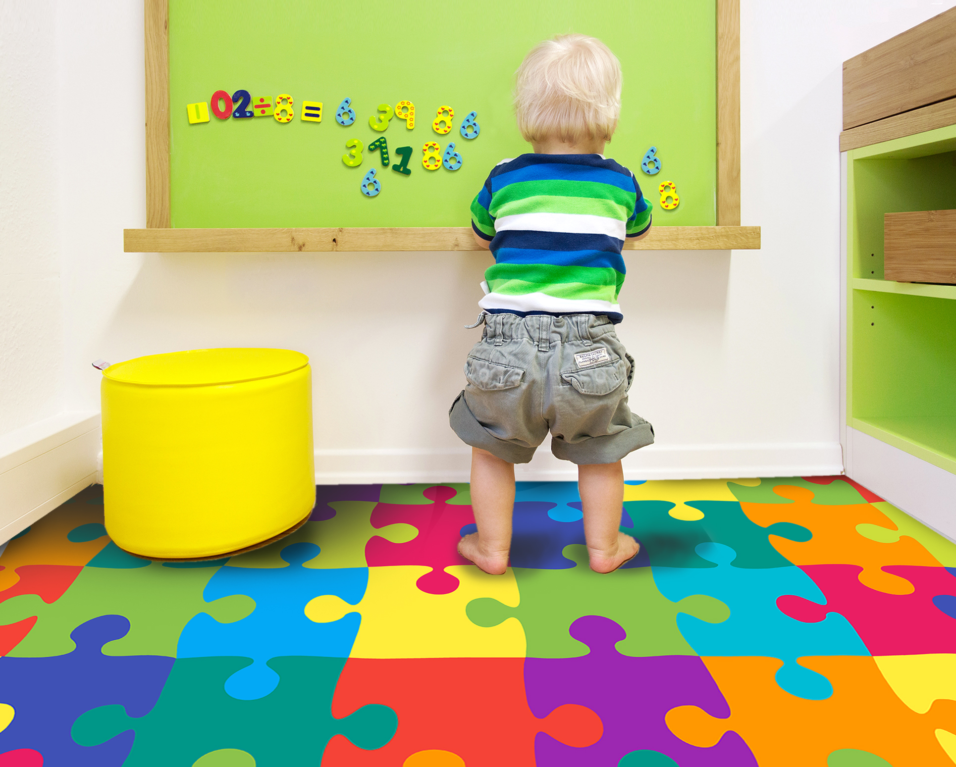 Kleinkind spielt im Kinderzimmer auf bunter Puzzlematte vor grüner Magnettafel mit Zahlen – idealer Spielboden für Lernen und Spielen