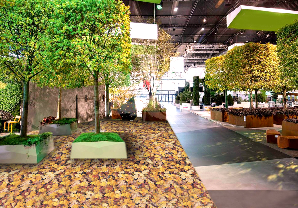 Indoor-Messestand mit großen Bäumen, Pflanzkübeln, Sitzbereichen und herbstlichem Laub-Bodenbelag als Inspiration für professionelle Innenraumbegrünung und Gestaltung.