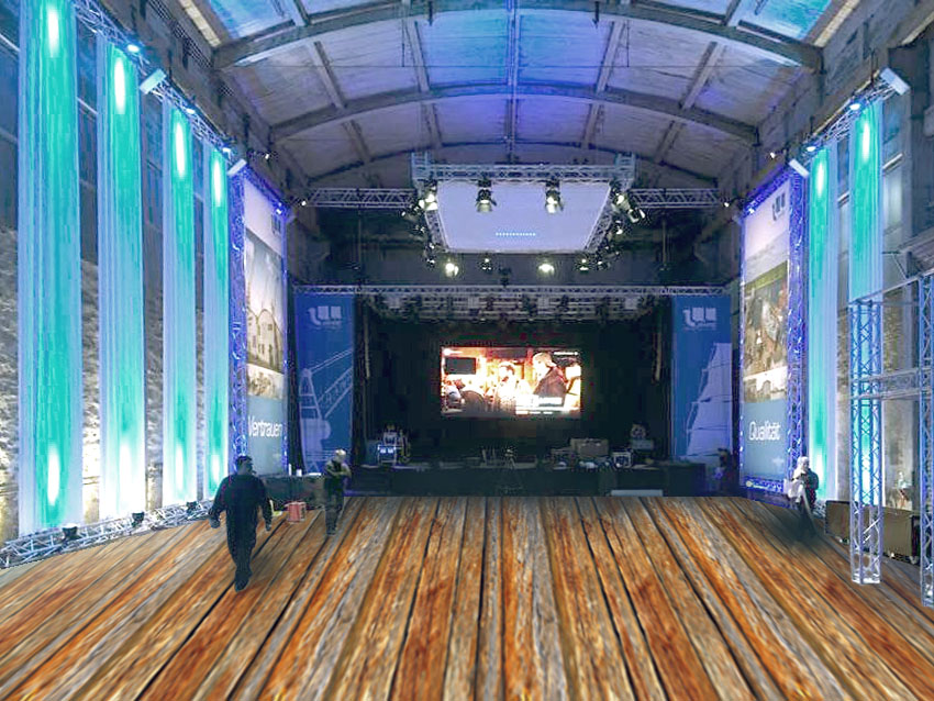 Große Veranstaltungshalle mit Holzboden, Bühne, LED-Videowand, Traversen und farbiger Beleuchtung als Beispiel für professionelle Eventtechnik und Bühnenbau.