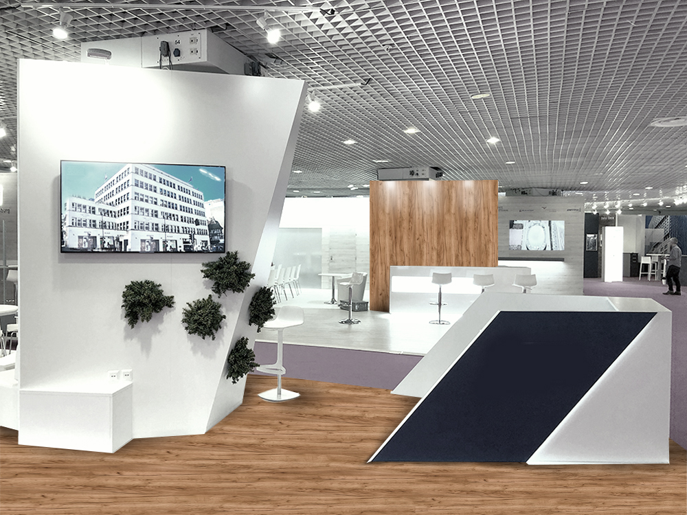 Heller moderner Messestand mit Holzoptik-Boden, weißen Präsentationsflächen, Monitor, Pflanzenwand und Lounge-Bereich für professionelle Messeauftritte